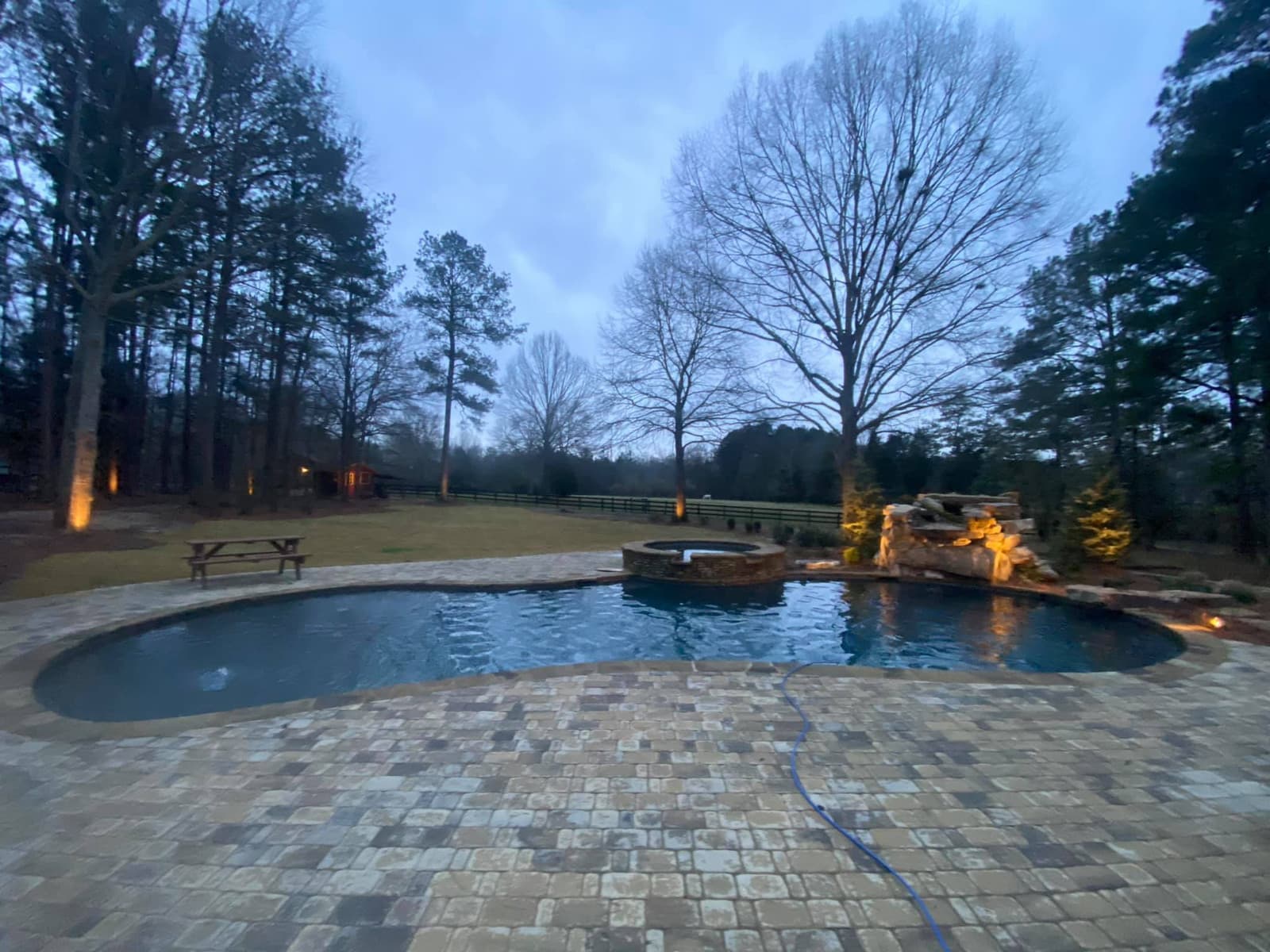 A renovated pool with fire bowls and a raised spa at dusk
